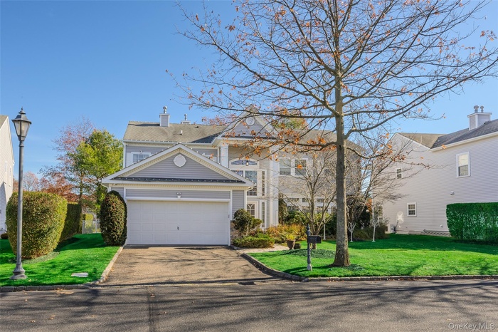 Traditional-style home with asphalt driveway, a chimney, a front yard, and an attached garage