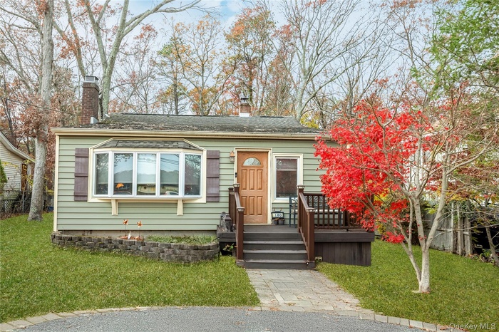 View of front of property featuring a chimney, a front yard, and a shingled roof