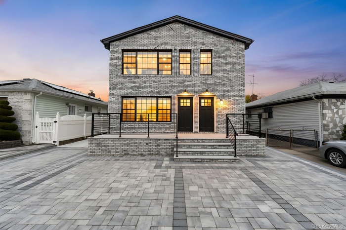 Contemporary home featuring a gate and brick siding