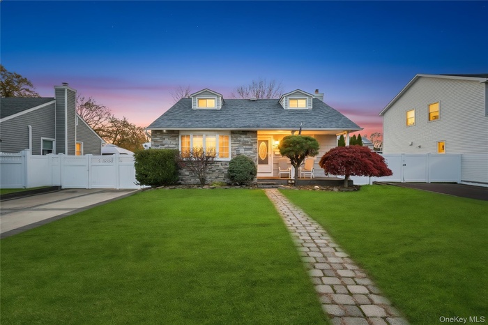View of front of property with stone siding, covered porch, a gate, a chimney, and roof with shingles