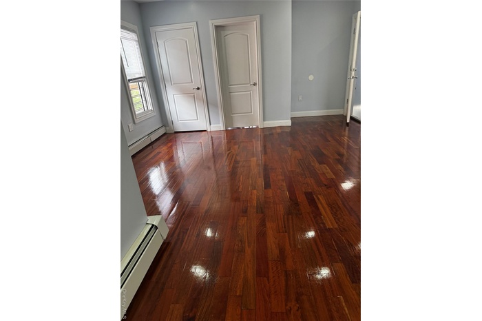 Unfurnished bedroom with a baseboard heating unit and dark wood-style floors