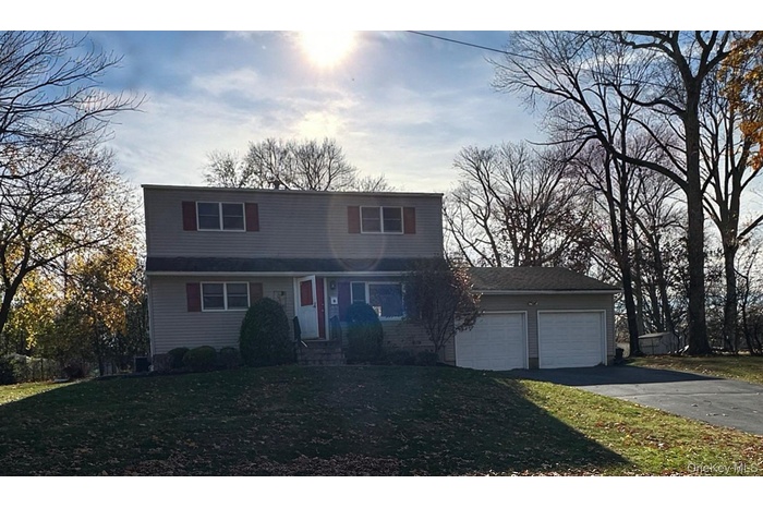 Traditional-style house with asphalt driveway, a garage, and a front yard
