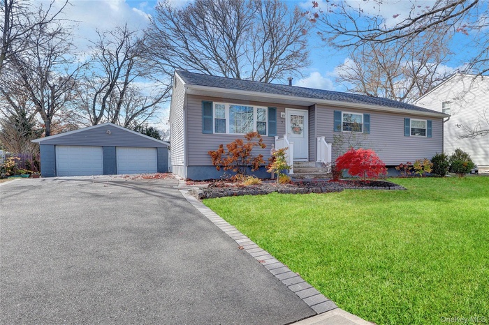 View of front of house with an outdoor structure, a front yard, a detached garage, and roof with shingles