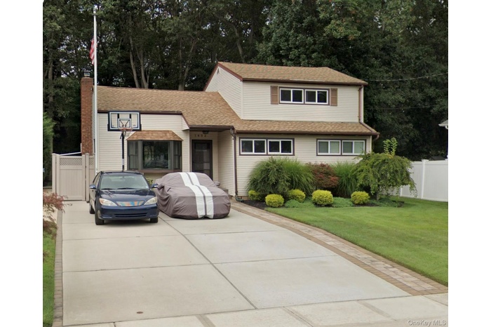 Traditional-style house with view of wooded area, roof with shingles, and a chimney