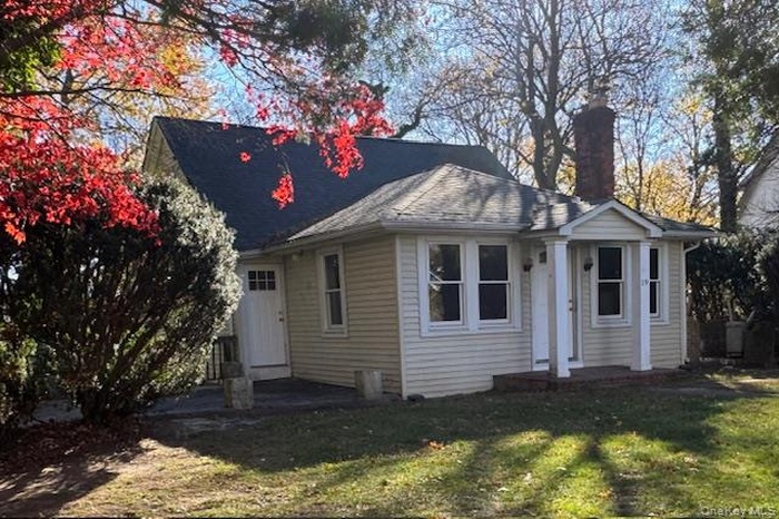 View of front of home featuring a chimney, a front lawn, and a patio