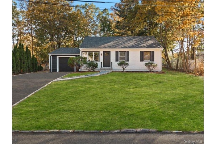 Ranch-style home with a front yard, asphalt driveway, and an attached garage