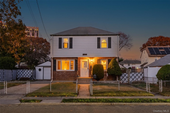Colonial-style house with a gate, brick siding, a fenced front yard, and a garage