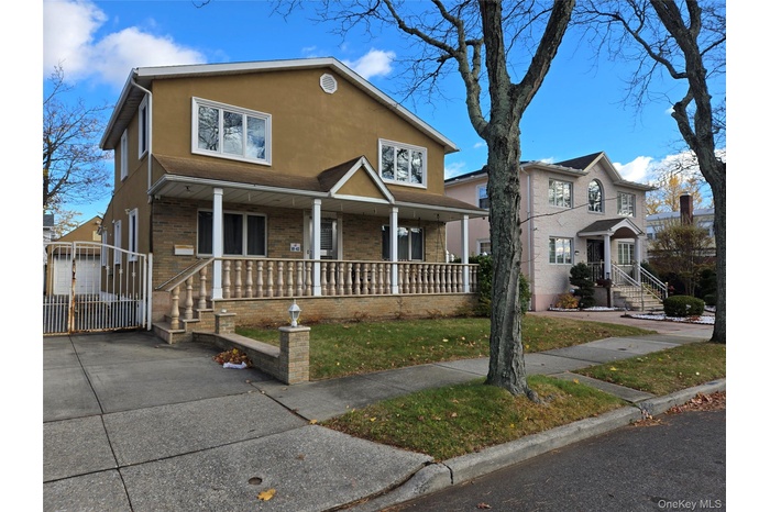 Traditional-style house featuring a porch, stucco siding, brick siding, a gate, and a front yard