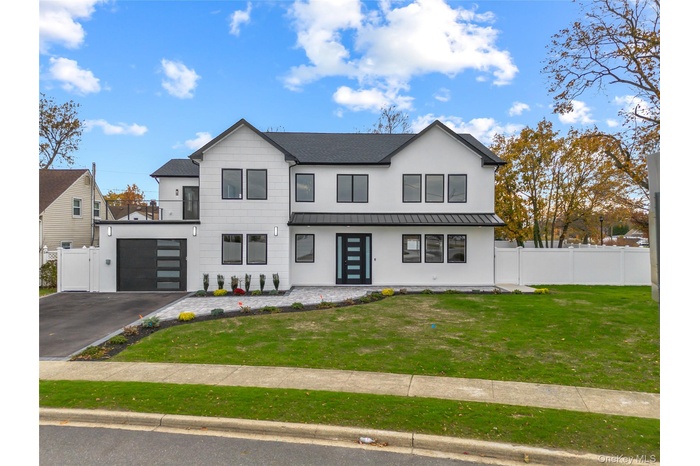 Modern farmhouse with a metal roof, a standing seam roof, asphalt driveway, stucco siding, and an attached garage