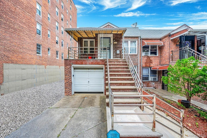 View of front of property with stairway, concrete driveway, an attached garage, brick siding, and a balcony
