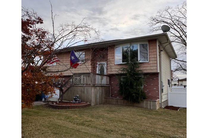 Back of property featuring a wooden deck, a yard, and brick siding