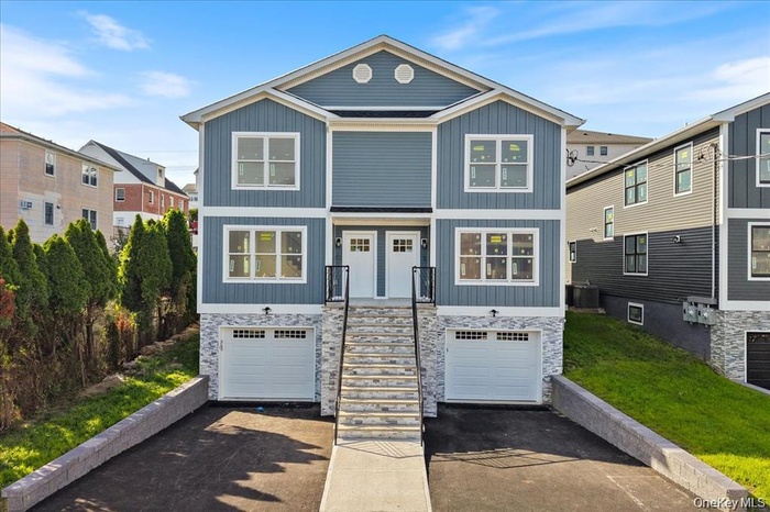 Craftsman-style home featuring a residential view, asphalt driveway, stone siding, stairs, and a garage