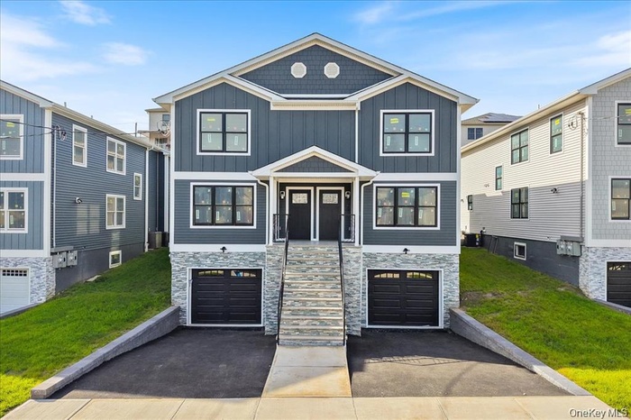 View of front facade with stone siding, board and batten siding, and an attached garage