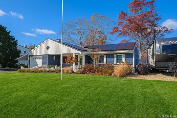 View of front facade featuring a front lawn, a garage, solar panels, and board and batten siding