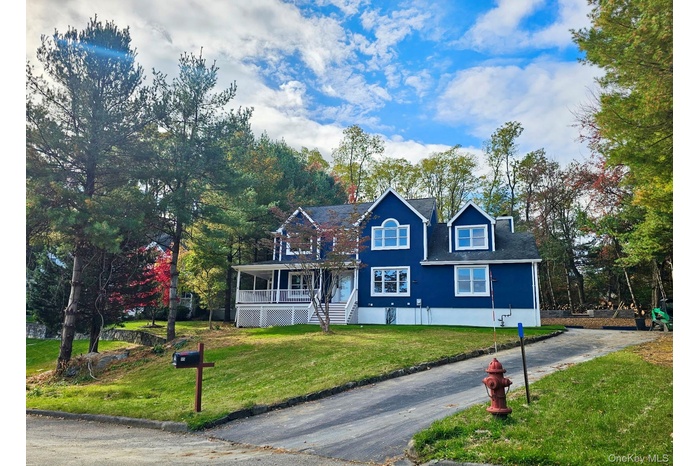 Traditional-style house featuring a front lawn, covered wrap around  porch, and driveway