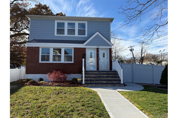 View of front of house with roof with shingles, brick siding, and a gate