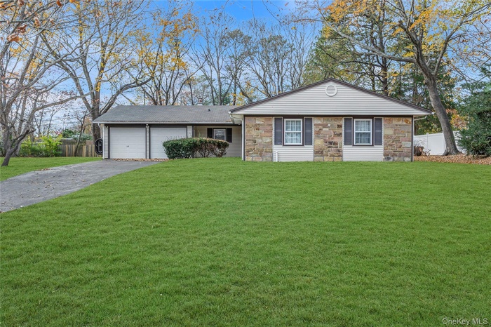 Ranch-style house featuring asphalt driveway, stone siding, and an attached garage