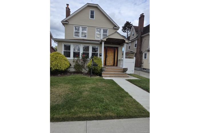 American foursquare style home featuring a front lawn and a chimney