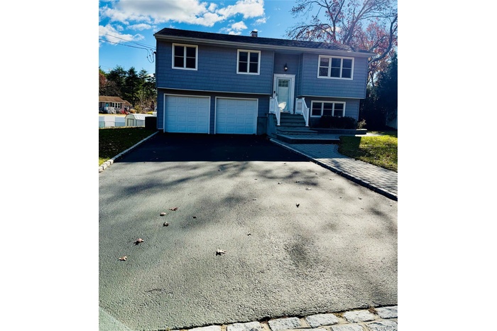 Raised ranch with asphalt driveway and an attached garage