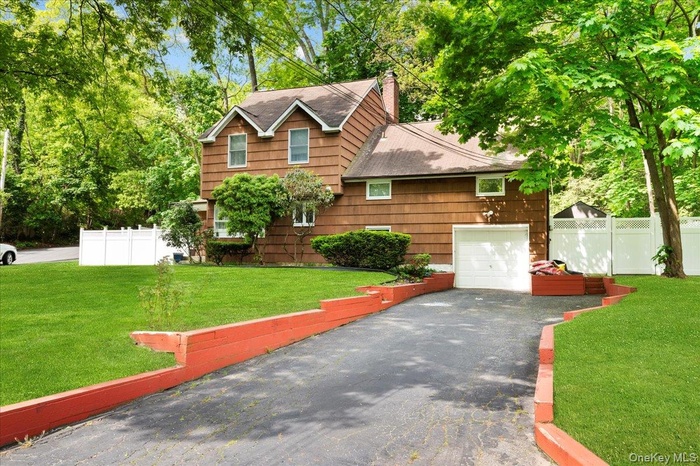 View of front facade featuring asphalt driveway, an attached garage, roof with shingles, and a chimney