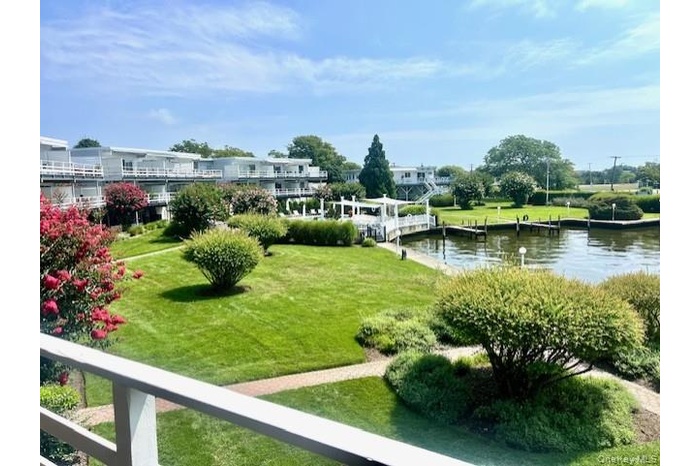View of community with a boat dock, a lawn, and a water view
