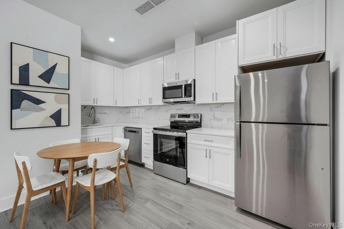 Kitchen w/ Quartz countertops, White Cabinets & Stainless-Steel Appliances - Virtually Staged