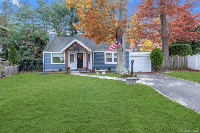 Bungalow-style house with a chimney, driveway, roof with shingles, and an attached garage