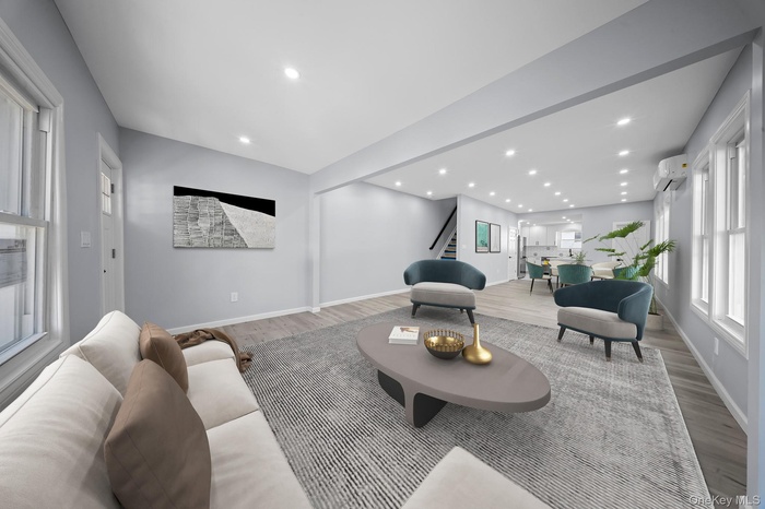 Living area with stairs, wood finished floors, a wall mounted AC, recessed lighting, and baseboards