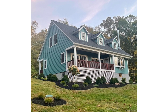 New england style home with covered porch, a front lawn, and a shingled roof