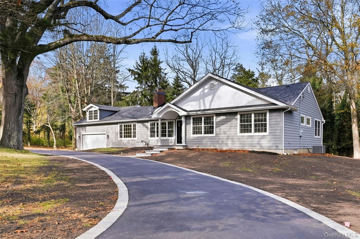 Ranch-style house featuring a chimney, a garage, asphalt driveway, and roof with shingles