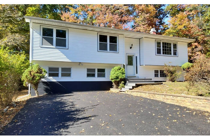 Bi-level home featuring a chimney and driveway