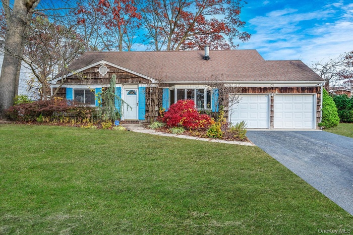 Ranch-style home with asphalt driveway, a front yard, roof with shingles, and an attached garage