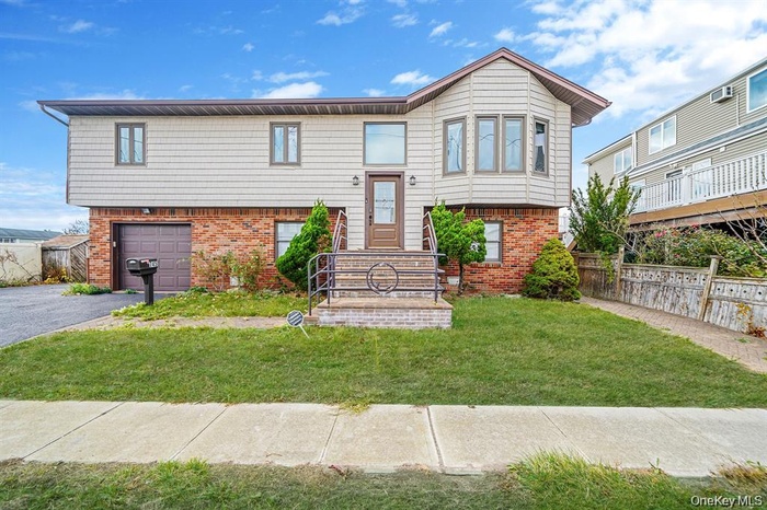 Split foyer home featuring brick siding, asphalt driveway, and an attached garage