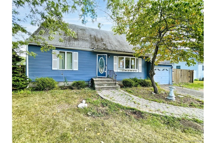 View of front facade with a garage, a shingled roof, and driveway
