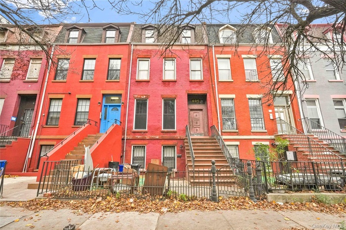 View of front of home with a fenced front yard, mansard roof, and stairway