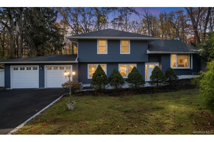 Tri-level home featuring a garage, asphalt driveway, and a yard