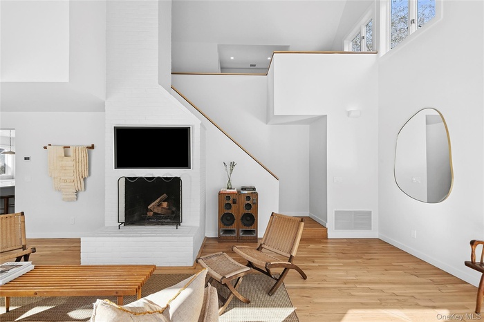 Living area featuring a high ceiling, light wood-style flooring, and a fireplace
