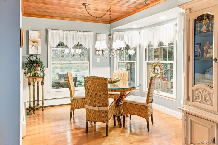 Dining room with wood ceiling, light wood finished floors, ornamental molding, a chandelier, and a baseboard heating unit