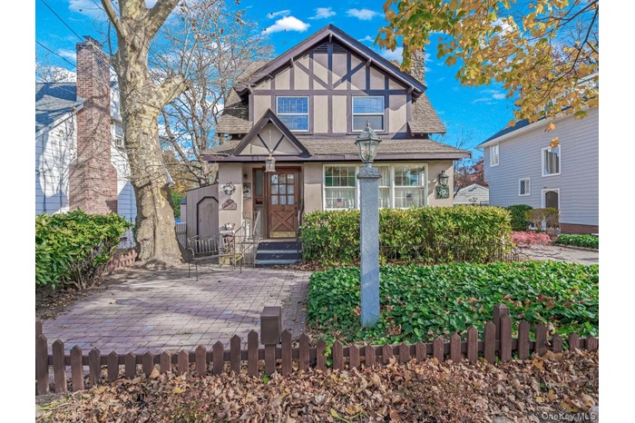 English style home with stucco siding, a fenced front yard, and a shingled roof