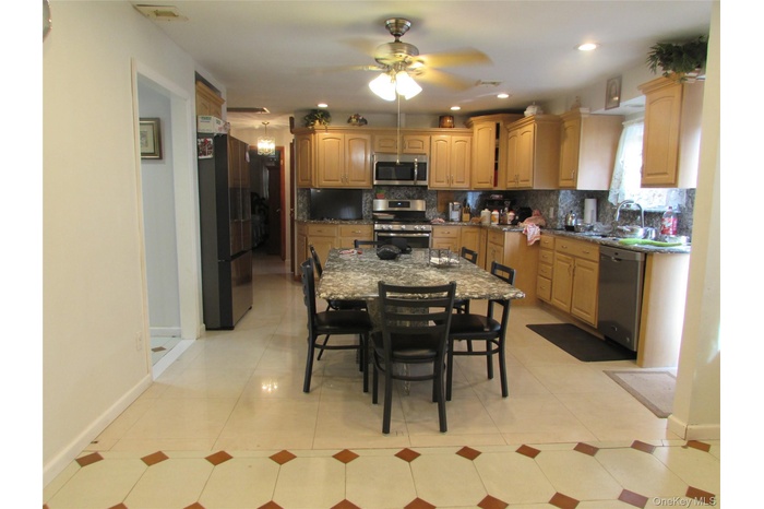 Kitchen featuring appliances with stainless steel finishes, decorative backsplash, dark stone counters, a ceiling fan, and recessed lighting
