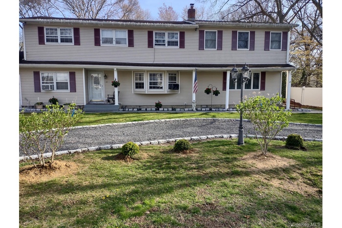 Traditional-style house featuring a porch, a front yard, and a chimney
