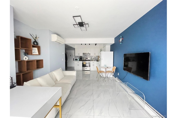 Living area with a baseboard radiator, light marble finish floors, and a wall mounted AC