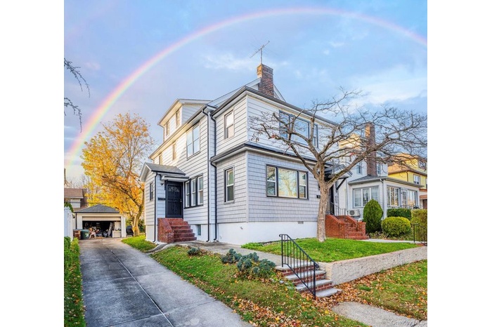 View of front facade featuring an outdoor structure, a detached garage, a chimney, and a front lawn