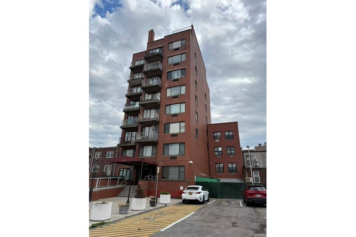 View of apartment building / complex featuring uncovered parking