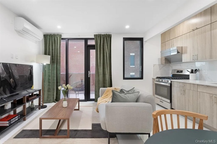 Kitchen featuring light brown cabinetry, modern cabinets, floor to ceiling windows, an AC wall unit, and range hood