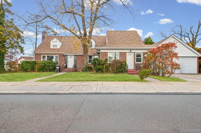 View of front of home with a front lawn, brick siding, a chimney, and a shingled roof