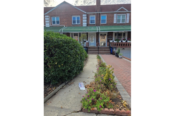 View of front of house featuring a porch, brick siding, and a chimney