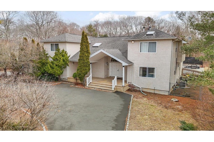 Traditional home with brick siding, roof with shingles, central AC, and fence