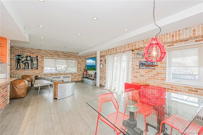 Dining area featuring brick wall, light wood-style floors, and recessed lighting