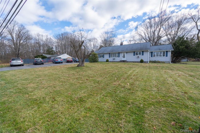 View of front of property with a chimney, a front lawn, and asphalt driveway